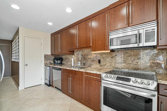 kitchen featuring light tile patterned floors, a sink, light stone countertops, stainless steel appliances, and backsplash