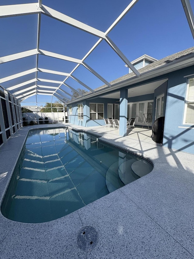 view of swimming pool with glass enclosure and a patio area