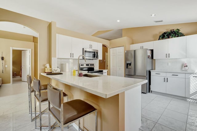 kitchen featuring white cabinets, stainless steel appliances, a breakfast bar area, and sink