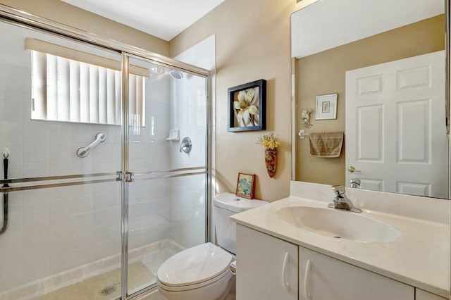 bathroom with toilet, vanity, and a shower with door
