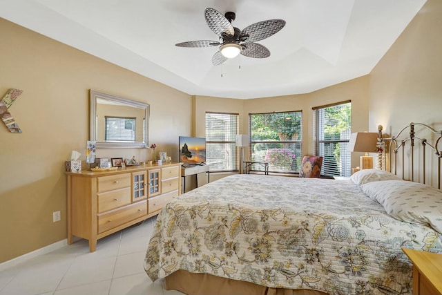 tiled bedroom with a tray ceiling and ceiling fan