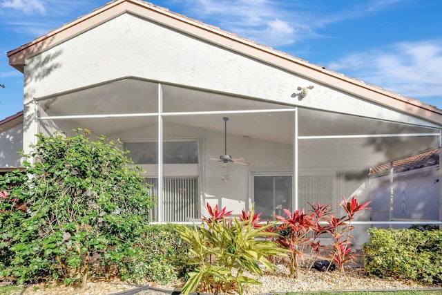 view of side of property with ceiling fan and a lanai