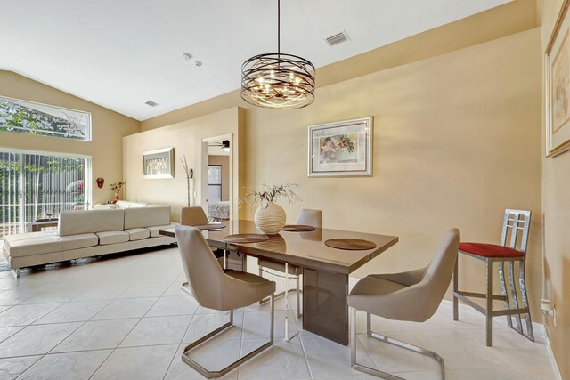 dining area with light tile patterned floors, a chandelier, and lofted ceiling