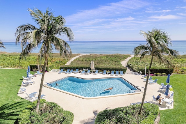 pool featuring a water view, a patio, and a lawn