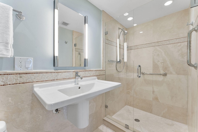 bathroom with a stall shower, a sink, visible vents, and tile walls