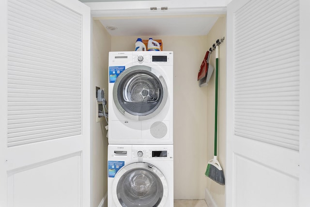 clothes washing area with stacked washer and dryer and laundry area