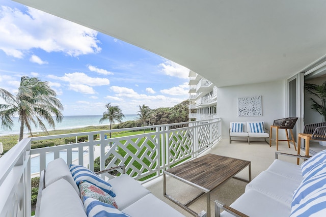 balcony with a water view, a view of the beach, and an outdoor living space