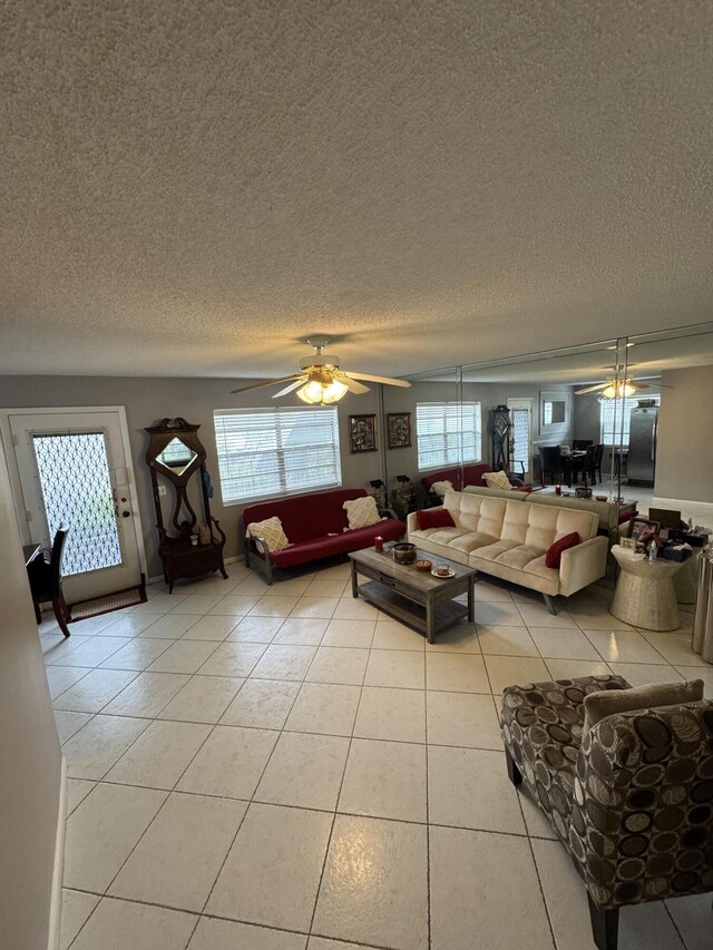 living room with ceiling fan, a textured ceiling, and light tile patterned floors