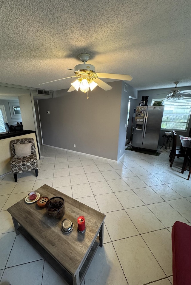 living room with ceiling fan, a textured ceiling, and light tile patterned floors