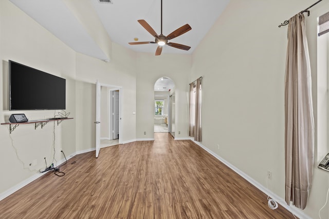 3036 Calle Valencia, West Palm Beach, FL 33409 - unfurnished living room featuring baseboards, a high ceiling, arched walkways, and wood finished floors