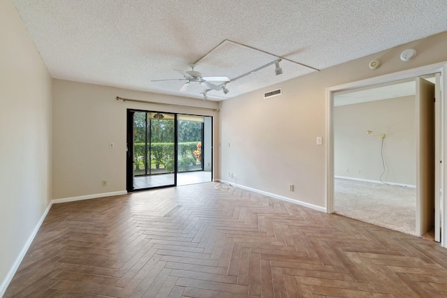 unfurnished room with rail lighting, visible vents, ceiling fan, and a textured ceiling