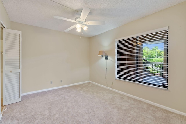 spare room featuring baseboards, a textured ceiling, and light colored carpet