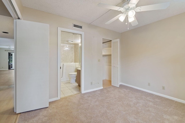 unfurnished bedroom featuring a closet, visible vents, light colored carpet, a textured ceiling, and baseboards