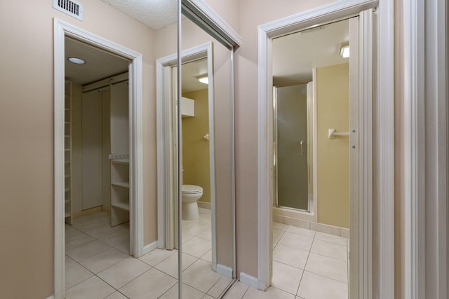 bathroom featuring toilet, visible vents, baseboards, tile patterned floors, and a stall shower