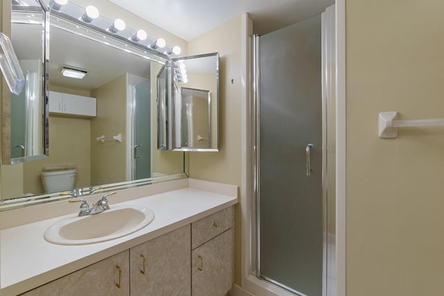 bathroom with a shower stall, vanity, and toilet