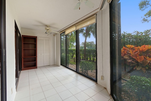 empty room with a sunroom, floor to ceiling windows, ceiling fan, and light tile patterned floors