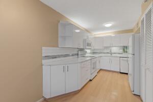 kitchen with white appliances, a sink, white cabinetry, light countertops, and light wood-type flooring