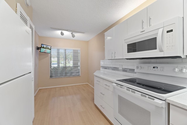 kitchen with a textured ceiling, white appliances, white cabinets, light countertops, and light wood finished floors