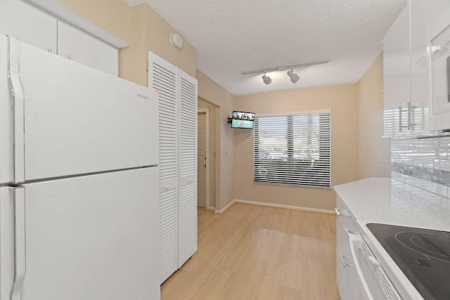 kitchen with white cabinetry, light countertops, a textured ceiling, and freestanding refrigerator