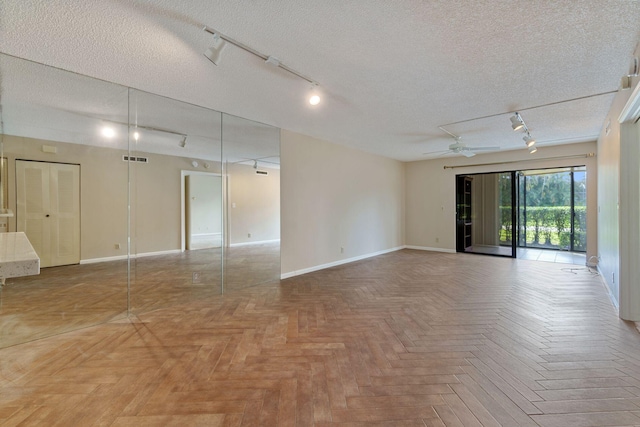 empty room featuring a ceiling fan, visible vents, a textured ceiling, and baseboards