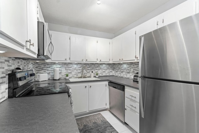 kitchen featuring stainless steel appliances, a sink, white cabinets, backsplash, and dark countertops