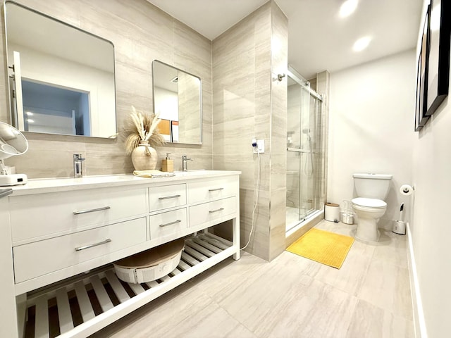 bathroom featuring tile walls, toilet, a shower with door, and vanity