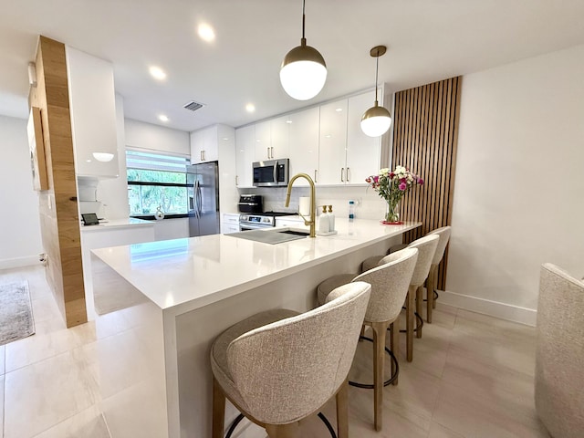 kitchen featuring appliances with stainless steel finishes, white cabinetry, a kitchen breakfast bar, kitchen peninsula, and hanging light fixtures