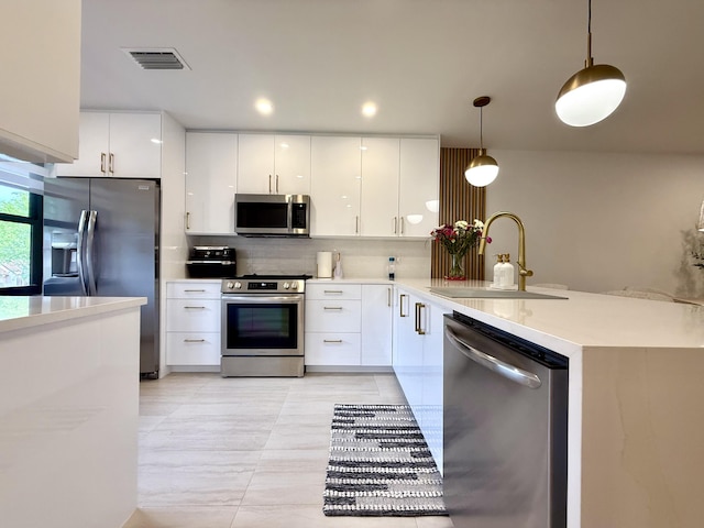 kitchen with sink, appliances with stainless steel finishes, white cabinetry, and pendant lighting