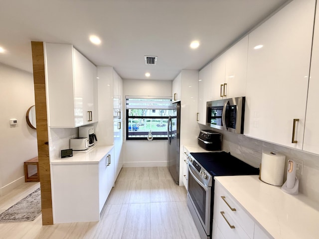 kitchen featuring backsplash, appliances with stainless steel finishes, and white cabinets