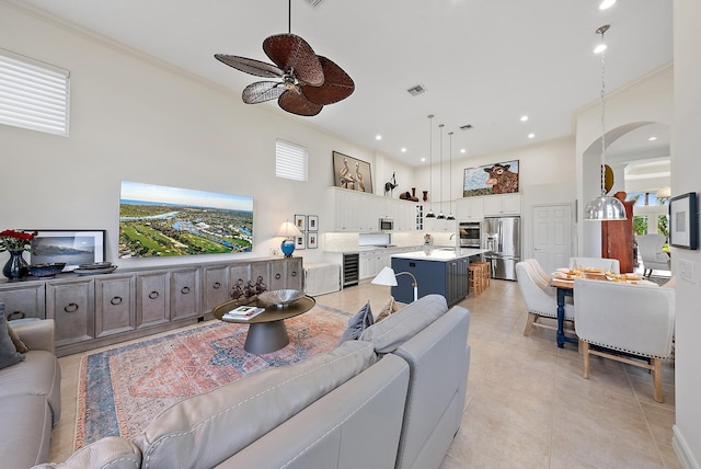 tiled living room with a high ceiling, ornamental molding, sink, ceiling fan, and beverage cooler