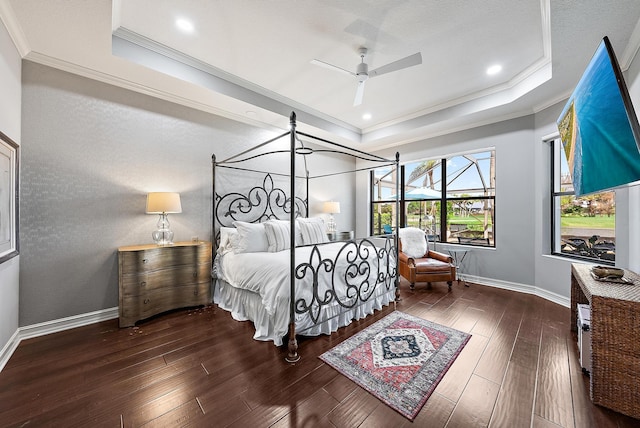 bedroom featuring a tray ceiling, ornamental molding, dark wood-type flooring, and ceiling fan