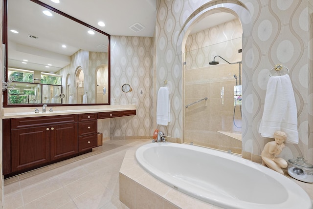 bathroom with tiled tub, vanity, and tile patterned floors