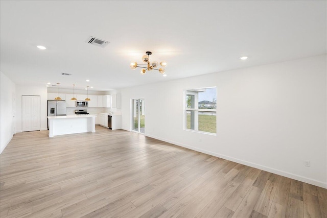 unfurnished living room with visible vents, baseboards, light wood-style flooring, an inviting chandelier, and recessed lighting