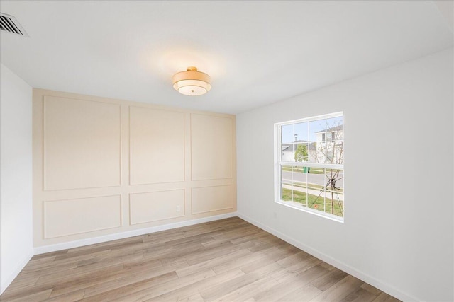 unfurnished bedroom with baseboards, light wood-type flooring, visible vents, and a decorative wall