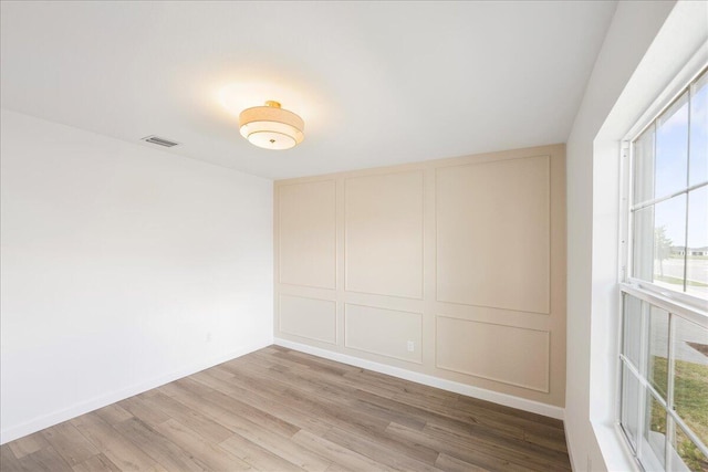 spare room featuring wood finished floors, visible vents, and baseboards