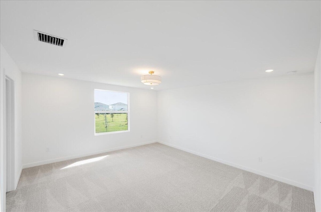 spare room with recessed lighting, visible vents, light carpet, and baseboards