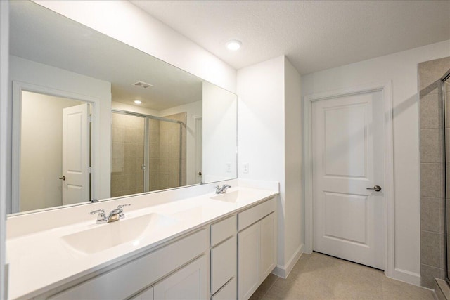 full bathroom featuring double vanity, a stall shower, and a sink