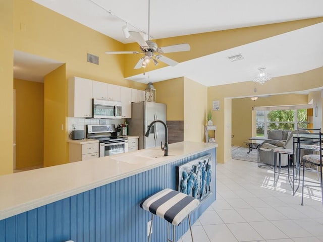 kitchen featuring sink, a breakfast bar, stainless steel appliances, white cabinets, and decorative backsplash