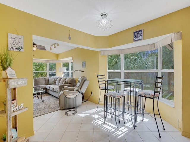 sunroom featuring ceiling fan with notable chandelier