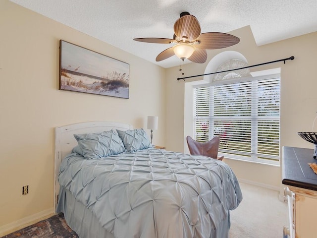 carpeted bedroom featuring ceiling fan and a textured ceiling