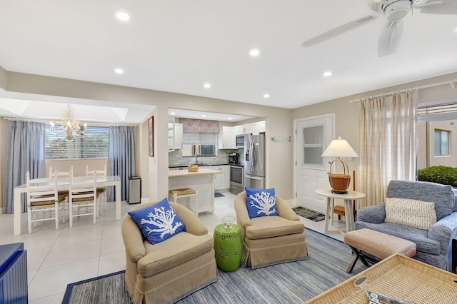 living room featuring ceiling fan with notable chandelier and light tile patterned floors