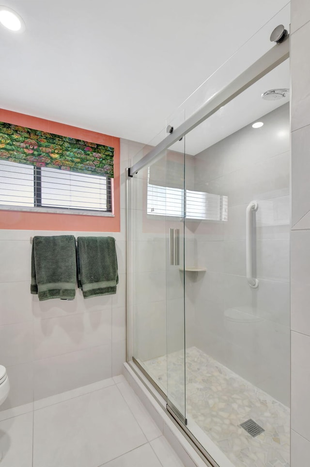 bathroom featuring tile patterned flooring, toilet, and a shower with door