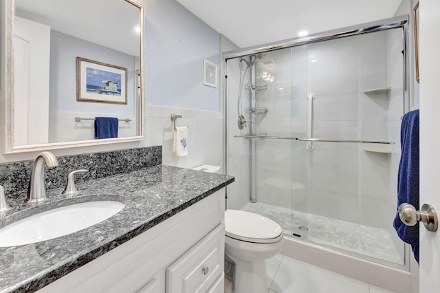 bathroom featuring tile patterned flooring, toilet, tile walls, vanity, and walk in shower