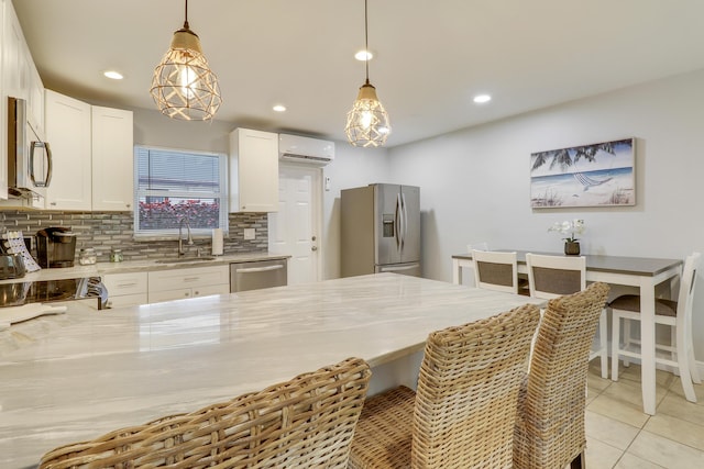 kitchen with sink, appliances with stainless steel finishes, white cabinets, and hanging light fixtures