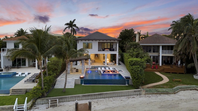 rear view of house with a balcony, a lawn, a patio, and a pool with connected hot tub