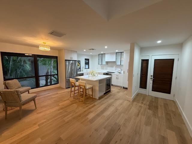 kitchen with stainless steel refrigerator, white cabinetry, a kitchen island, and a breakfast bar area