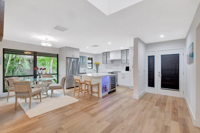 kitchen with light wood-style floors, beverage cooler, light countertops, and stainless steel refrigerator