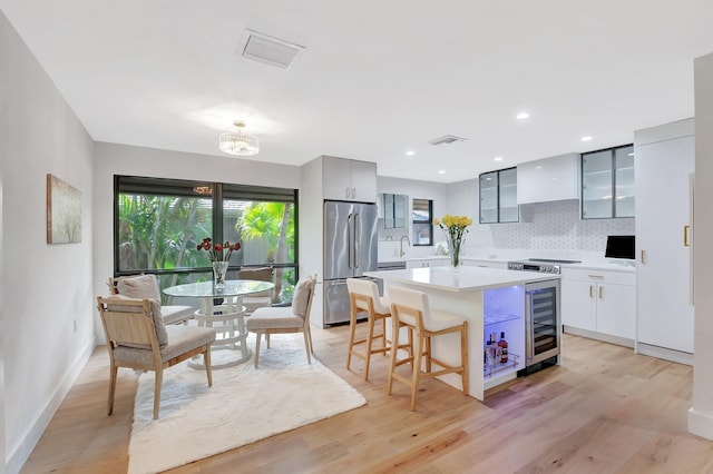 kitchen featuring modern cabinets, custom range hood, glass insert cabinets, and high end fridge