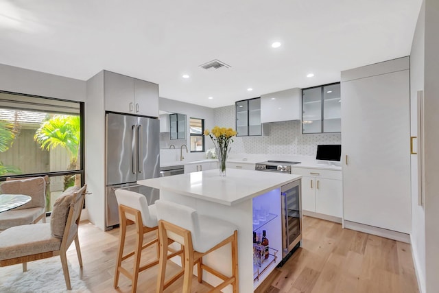 kitchen featuring stainless steel appliances, modern cabinets, custom exhaust hood, and visible vents