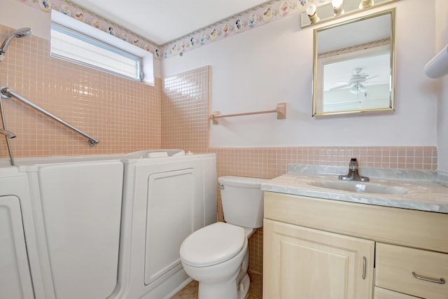 bathroom with toilet, tile walls, ceiling fan, and vanity